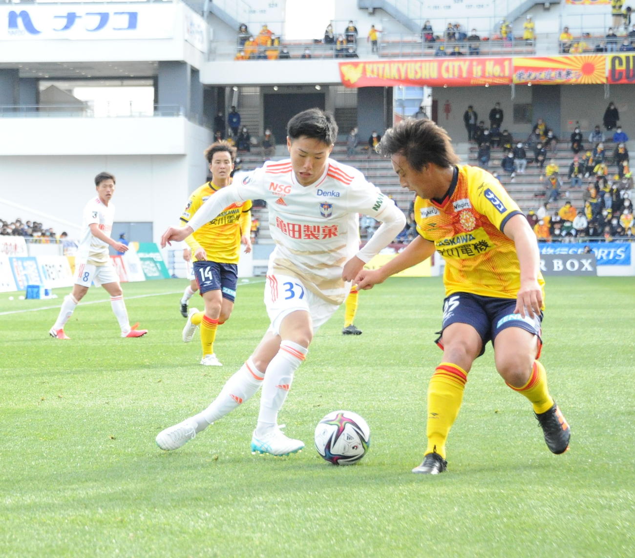 プロデビュー戦となった21年開幕・北九州戦でドリブルを仕掛ける三戸（手前左）