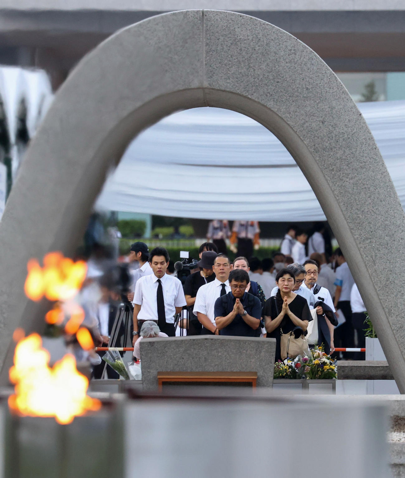 米軍の原爆投下から80年の「原爆の日」となり、慰霊碑に手を合わせる人たち＝6日午前5時33分、広島市中区の平和記念公園（共同）