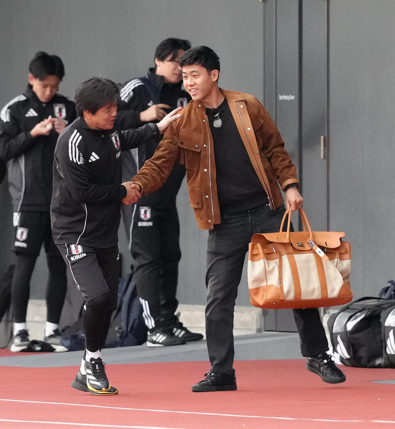 合流した遠藤（右）は名波コーチと笑顔で握手を交わす（撮影・足立雅史）