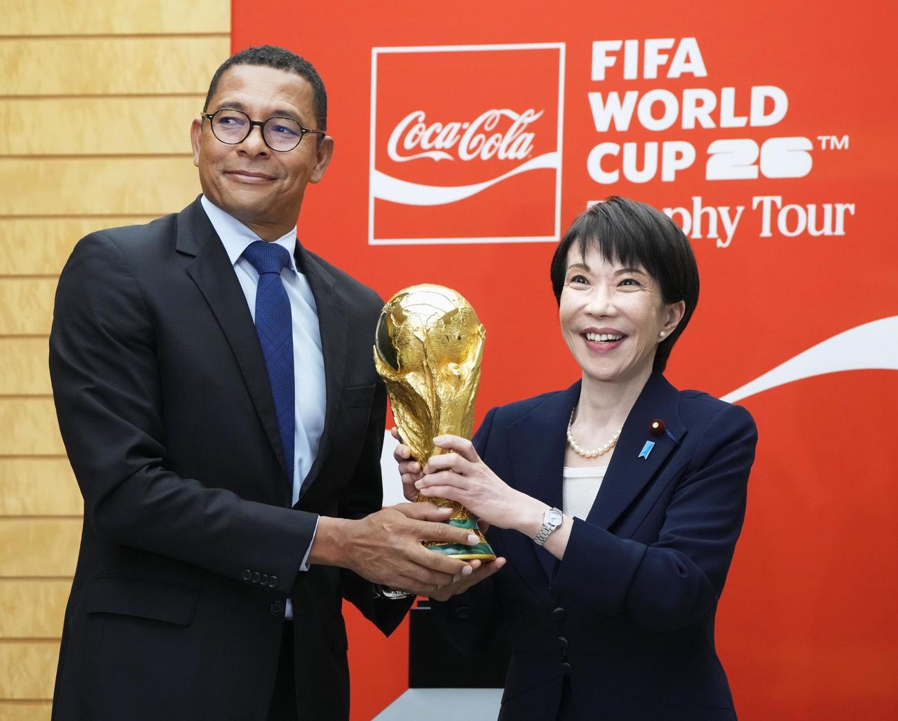 サッカーW杯の優勝トロフィーを持ち、ジウベルトシウバ氏（左）と写真撮影する高市首相（共同）