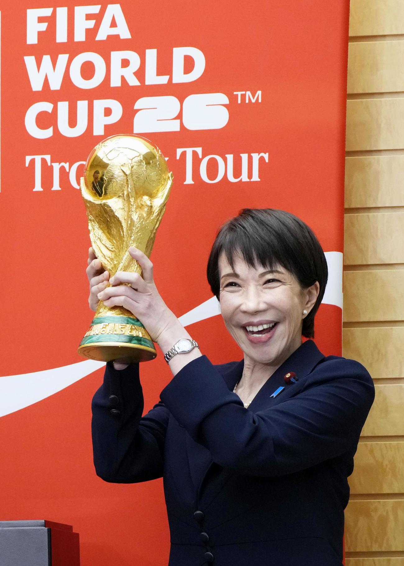 サッカーW杯の優勝トロフィーを持ち、写真撮影する高市首相（共同）