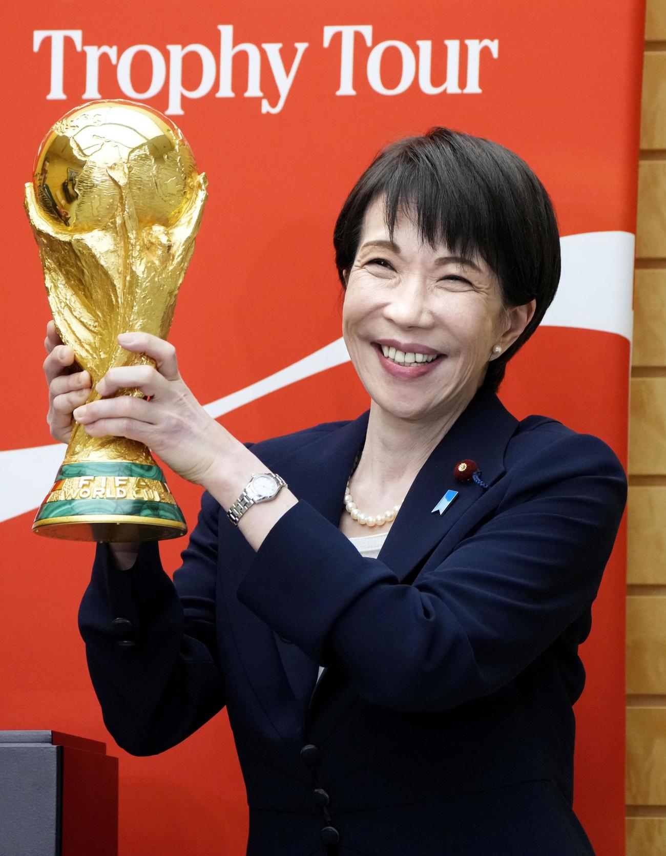 サッカーW杯の優勝トロフィーを持ち、写真撮影する高市首相（共同）