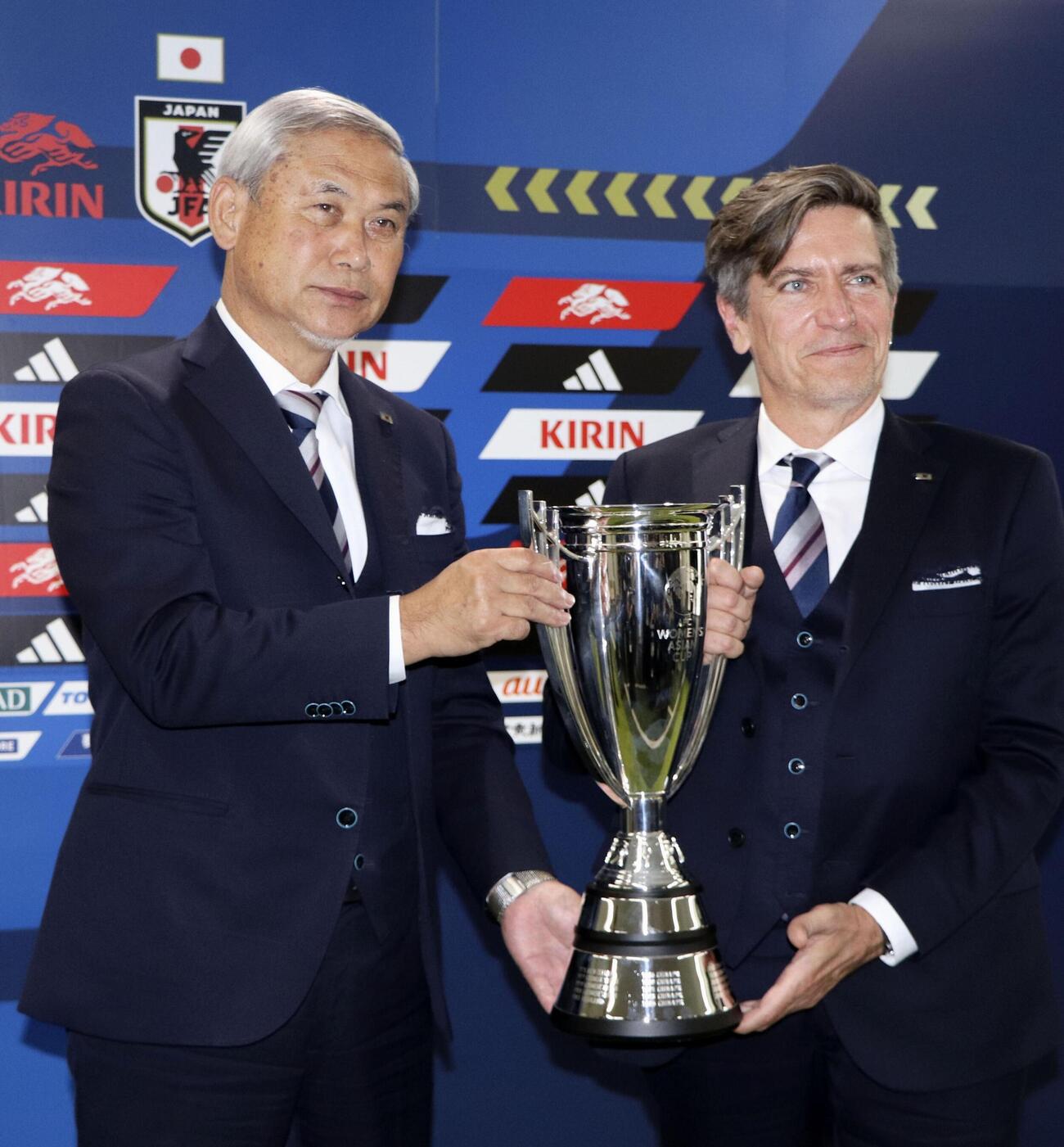 3月23日、女子アジア杯の優勝報告記者会見で写真に納まる日本サッカー協会の佐々木女子委員長（左）とニールセン監督