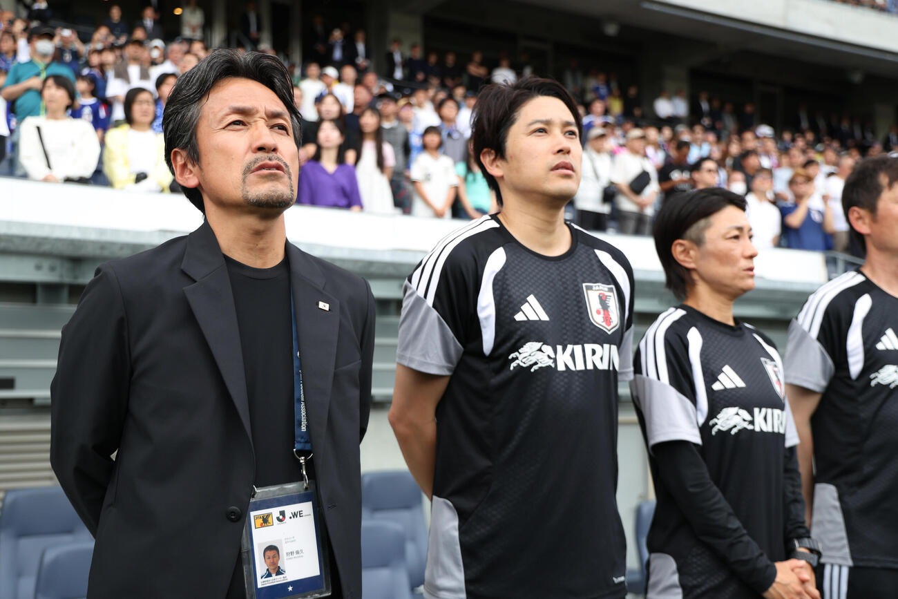 なでしこジャパン国際親善試合　日本対南アフリカ　試合前、君が代を歌う狩野倫久監督（左）。中央は内田篤人コーチ、右は近賀ゆかりコーチ（撮影・前田充）