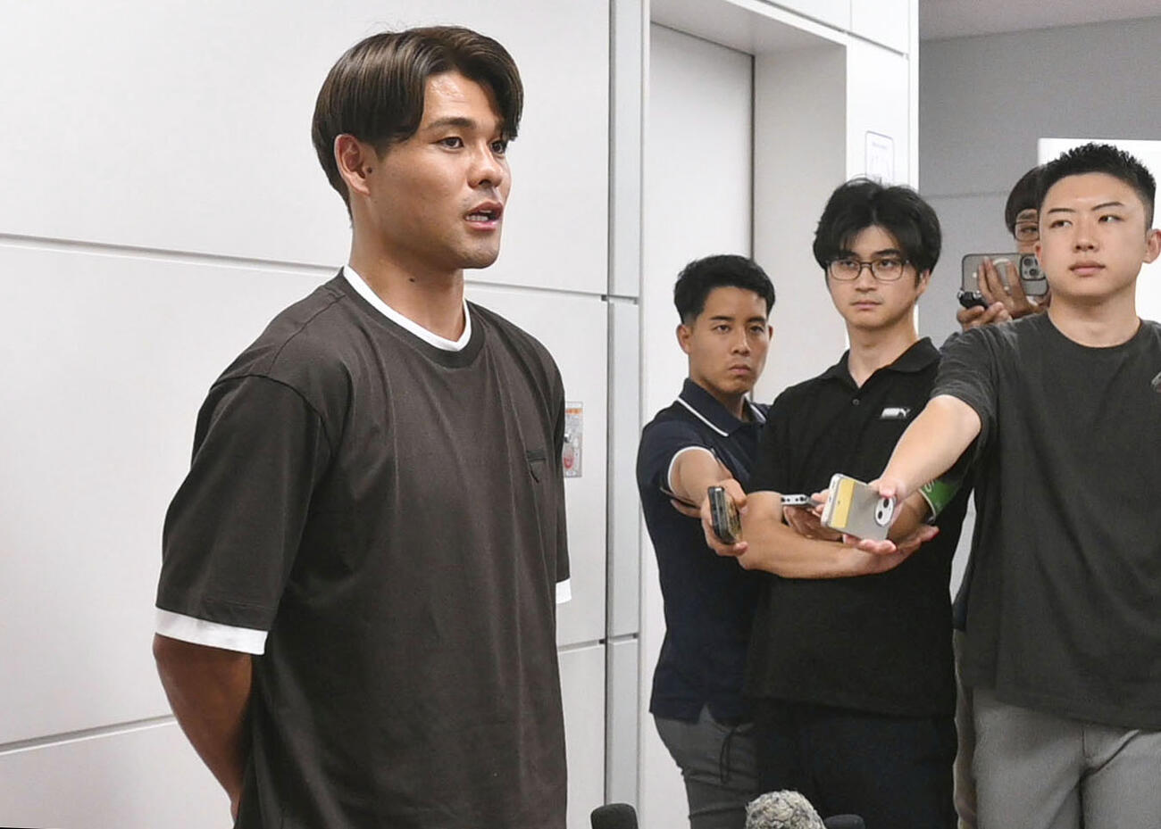 新シーズンに向けて渡欧する前に羽田空港で取材に応じるサッカー日本代表の佐野海舟（左端）＝24日（共同）