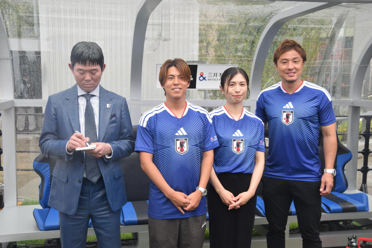森保一監督の等身大フィギュアと写真を撮る、左から森保圭悟さん、鮫島彩さん、那須大亮さん（2026年6月撮影）