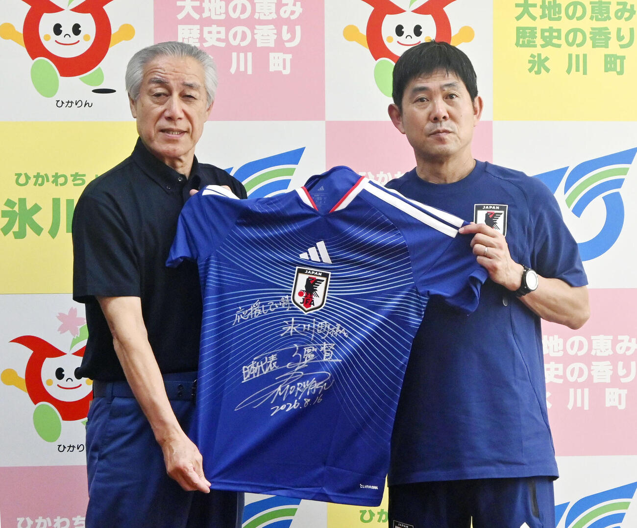 熊本県氷川町の藤本一臣町長（左）にサッカー日本代表のユニホームを手渡す森保監督＝16日、氷川町役場（共同）