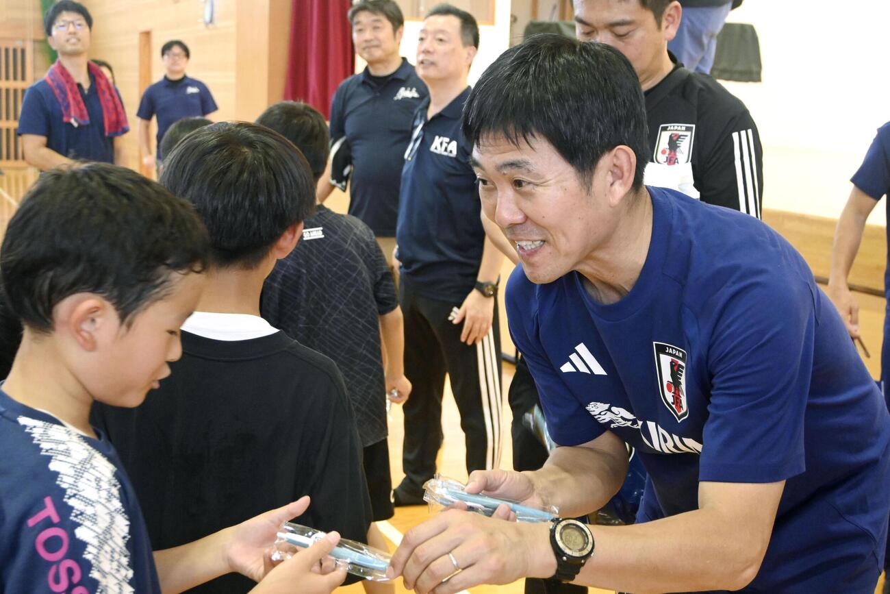 小中学生らにボールペンを手渡すサッカー日本代表の森保監督＝16日、熊本県氷川町（共同）