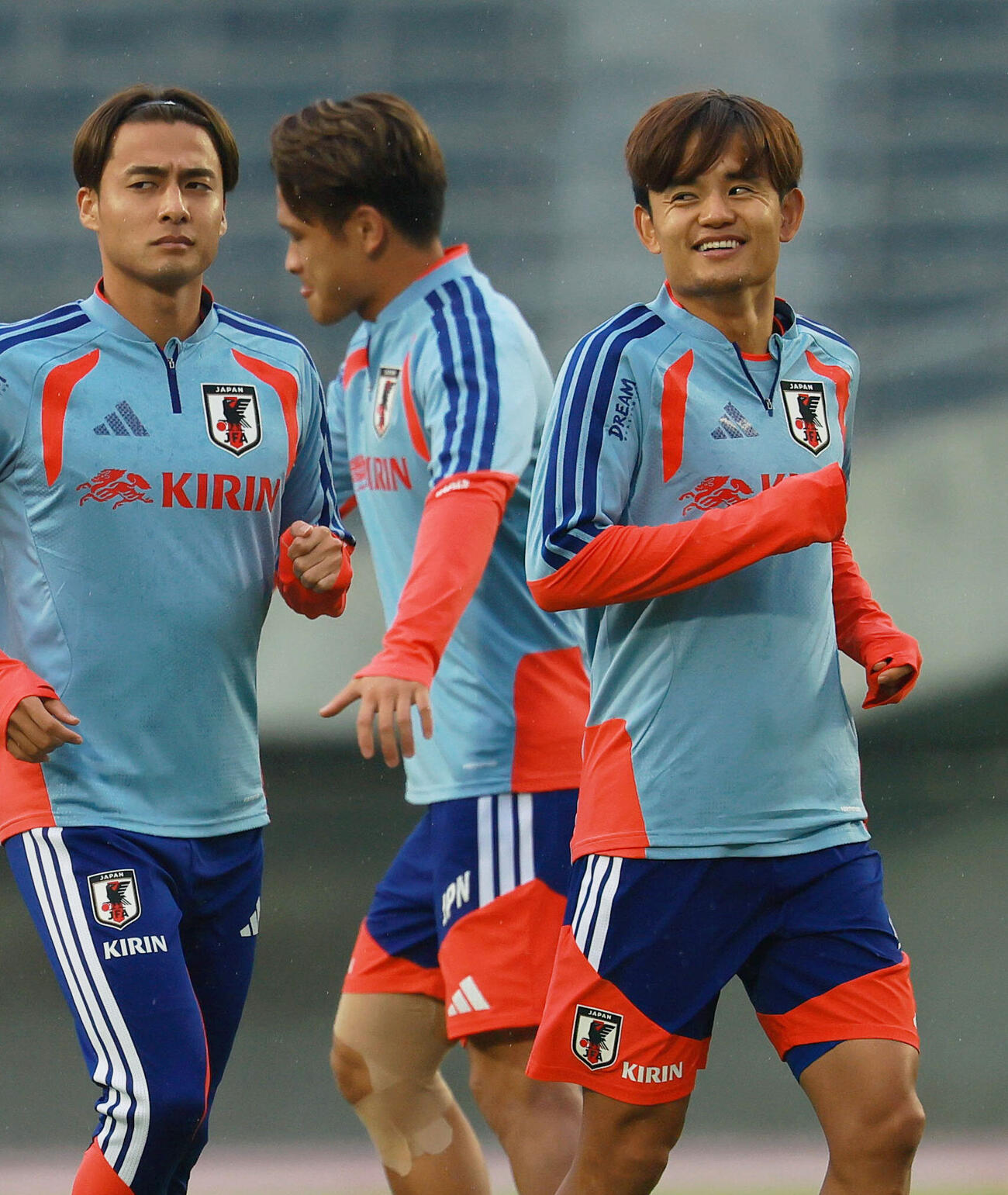 リラックスした表情でウオーミングアップを行う久保建英（右）と佐野航大（撮影・上山淳一）