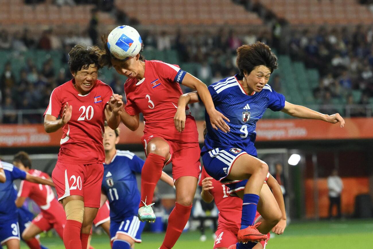 女子サッカー決勝　日本対北朝鮮　前半、ヘディングで競り合う上野真実（右）（撮影・滝沢徹郎）