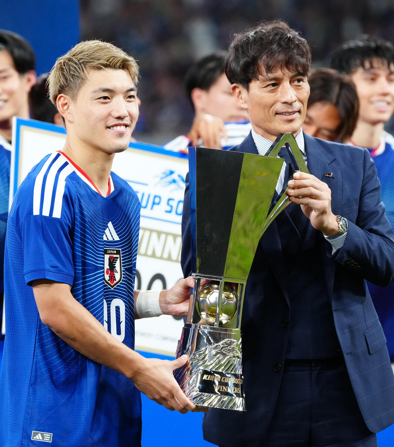 日本対ニュージーランド　キリン杯を手に日本サッカー協会宮本恒靖会長（右）と写真に納まる堂安律（撮影・江口和貴）