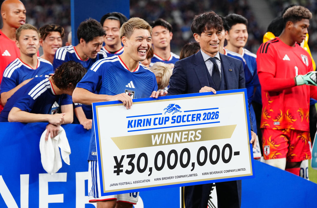 日本対ニュージーランド　日本サッカー協会宮本恒靖会長（右）から賞金ボードを受け取り、笑顔を見せる堂安律（撮影・江口和貴）
