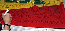 オシム監督に届けと球団旗にメッセージを書き込む千葉サポーター