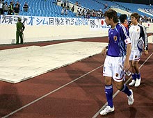 「頑張れオシム回復を祈る」と書かれた横断幕の前であいさつする選手たち
