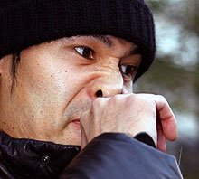 成田空港外で会見した高原は手を鼻に押しつけるしぐさを見せた