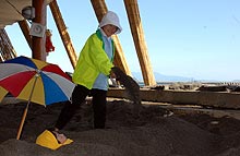 砂むし風呂の入浴客に砂をかける係員（撮影・為田聡史）