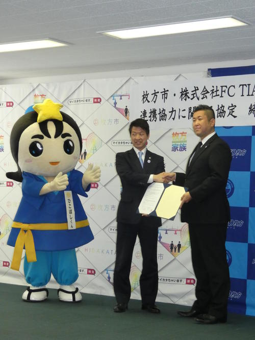 連携協力の協定を結んだ関西リーグ1部FCティアモ枚方の村島孝史社長（右）と伏見隆枚方市長。左は枚方市のキャラクターひこぼしくん（撮影・小杉舞）