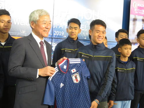 日本サッカーミュージアムを訪れた、昨年7月に「奇跡の生還」を果たしたタイのサッカーチームに記念品を贈呈するJFA大仁館長（左）