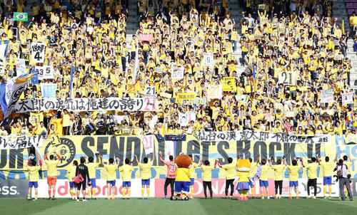仙台対広島　8日の試合で負傷した関憲太郎を応援する横断幕を掲げるサポーターと共にバンザイで喜ぶ仙台イレブン（撮影・浅見桂子）