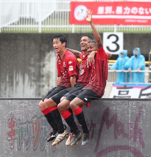 札幌対鳥栖　前半31分、得点を決めたFWジェイ（中央）は看板に座り、DF石川（左）FW鈴木と喜ぶ（撮影・黒川智章）