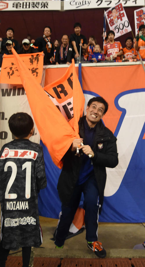 試合後、ゴール裏サポーターから手渡された応援旗を持ち笑顔の新潟GK野沢（撮影・山岸章利）