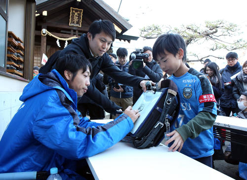 必勝祈願後、川崎市内の神社で子どもサポーターのランドセルにサインする川崎Fの中村憲剛（左）（撮影・浅見桂子）