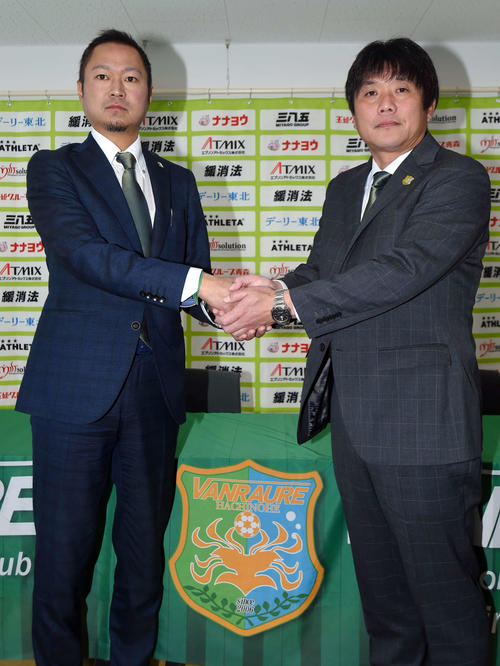 就任会見で握手を交わす中口新監督（右）と細越代表取締役