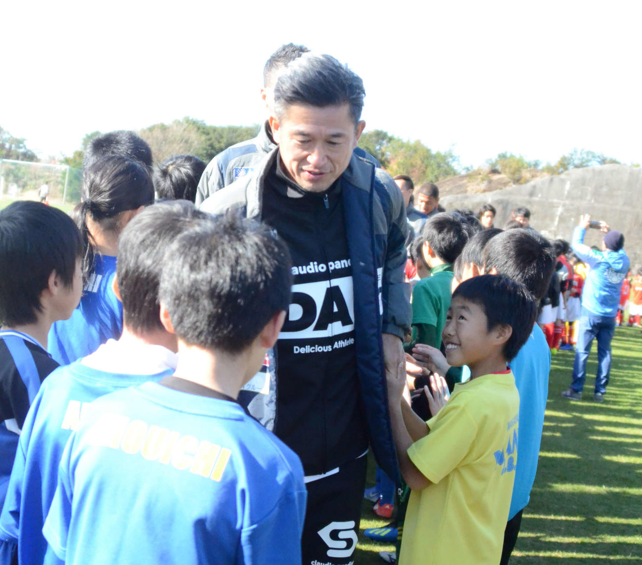 サッカースクールに参加した小学生たちとハイタッチをする横浜FCのFWカズ