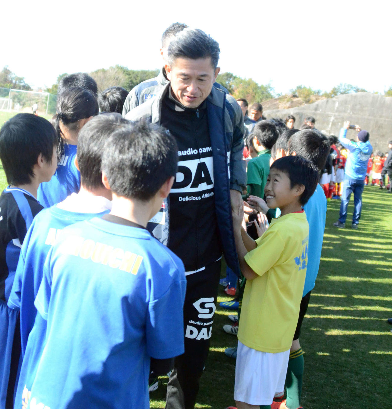 サッカースクールに参加した小学生たちとタッチをする横浜FC・FWカズ