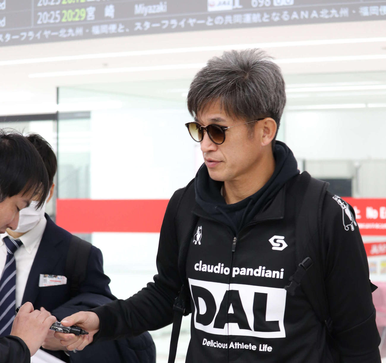 和歌山合宿から帰京した横浜FCのFWカズは空港で待ち受けたファンへサインに応じる