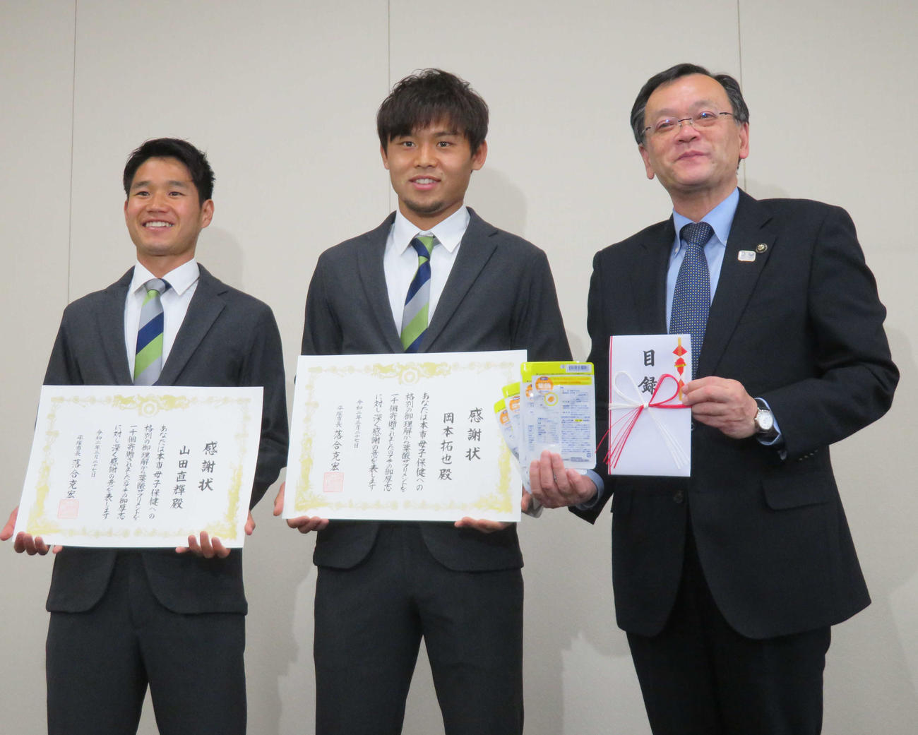 平塚市の落合市長（右端）に葉酸サプリメント寄贈の目録を手渡した湘南のDF岡本主将（中央）とMF山田