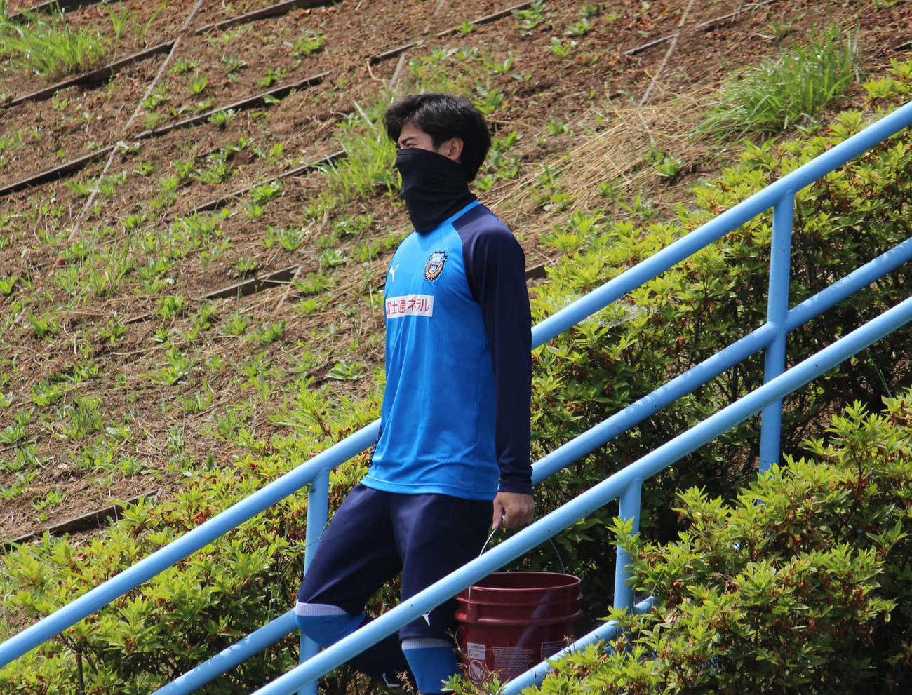 給水用のマイボトルが入ったバケツ状の容器を手にグラウンドへ向かう川崎F谷口