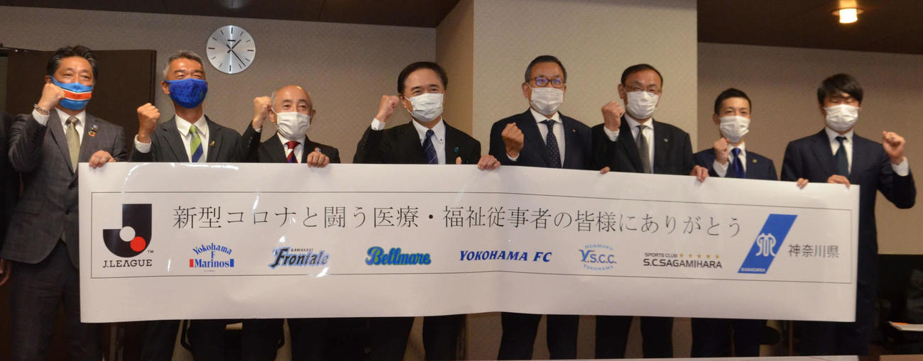医療従事者らへ向けた横断幕と共に記念撮影する黒岩知事（左から4人目）とJリーグの村井チェアマン（同5人目）と神奈川6クラブの代表者たち（撮影・松尾幸之介）