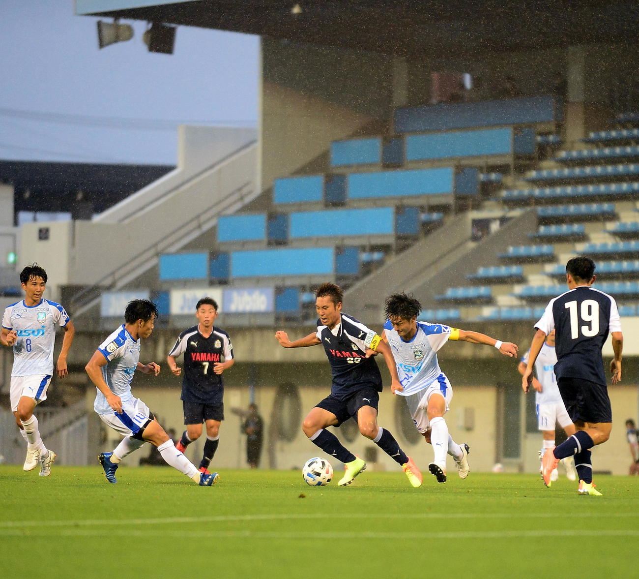 会場のスピーカー（左上）からリモート応援が響く中、プレーする磐田と沼津の選手たち