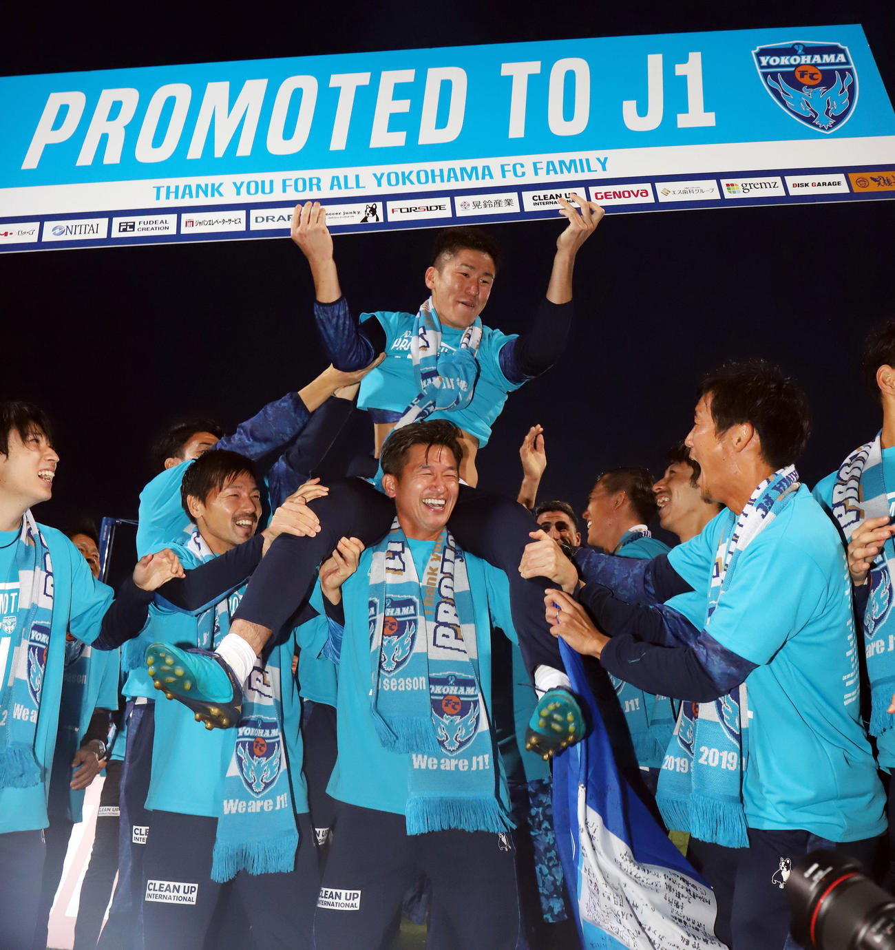19年11月、J1昇格のボードを持つ北爪（上）を肩車するカズ（三浦知良）