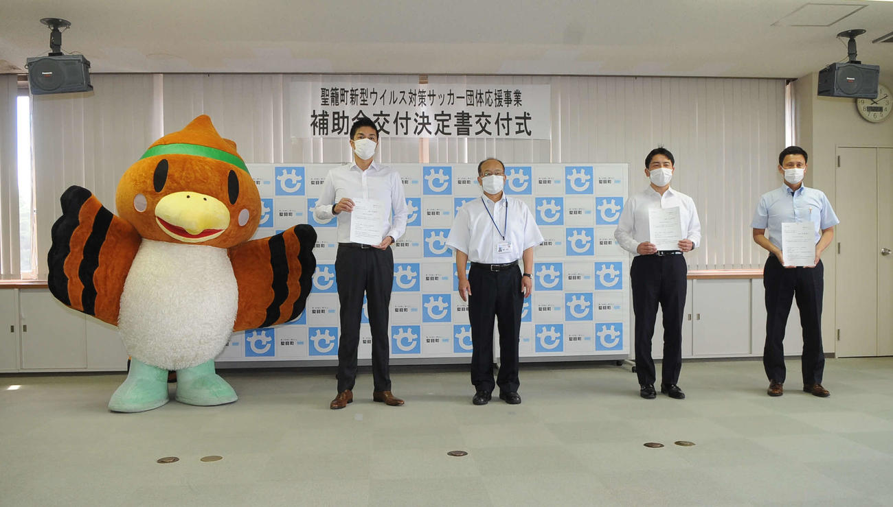 西脇町長（中央）を中心に記念撮影をする3クラブの代表。右から新潟L・山本社長、JSC・中村校長、1人置いてJ2新潟・是永社長。左は聖籠町のキャラクター、緑丸