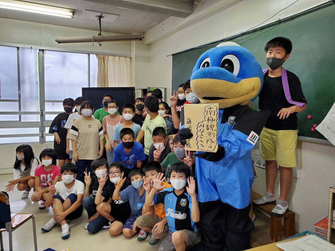 「南極教室」イベントに参加した藤崎小学校の6年1組の生徒と記念撮影をする川崎Fのマスコットふろん太