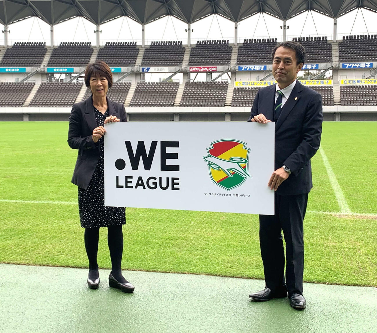 スタジアムで記念撮影するWEリーグの岡島チェア（左）と千葉の森本社長