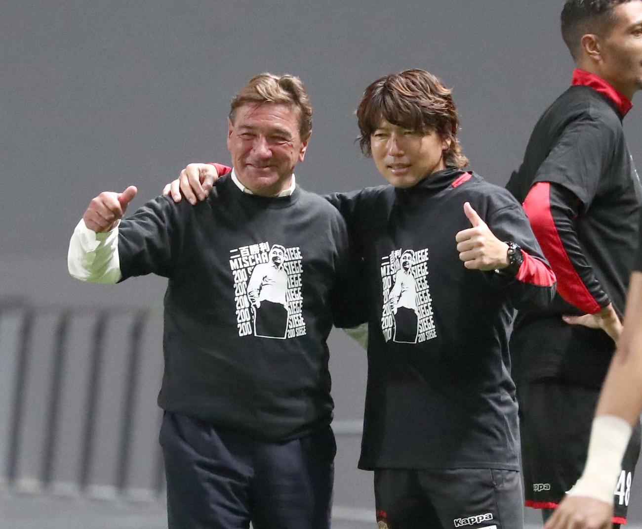 札幌対横浜FC　試合後、200勝記念Tシャツを着て記念撮影する杉浦コーチ兼通訳（右）とペトロビッチ監督（撮影・黒川智章）