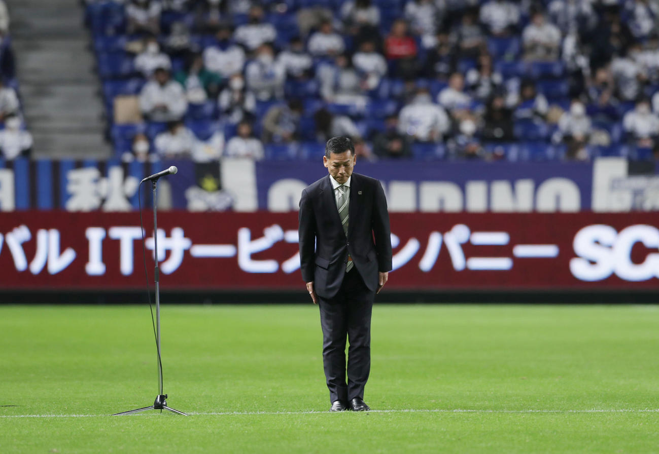 選手がウオーミングアップを終えピッチから引き揚げる中、G大阪FWアデミウソンの不祥事について謝罪する小野社長（撮影・前田充）