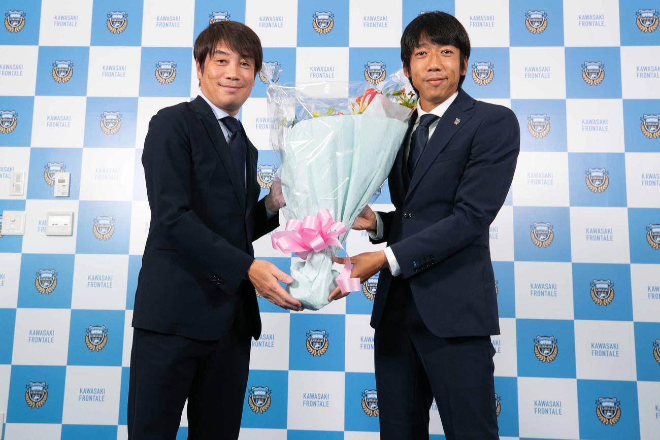 引退会見を終えて、インタビュアーを務めた中西哲生氏（左）から花束を受け取る川崎フロンターレMF中村憲剛（C）KAWASAKI　FRONTALE