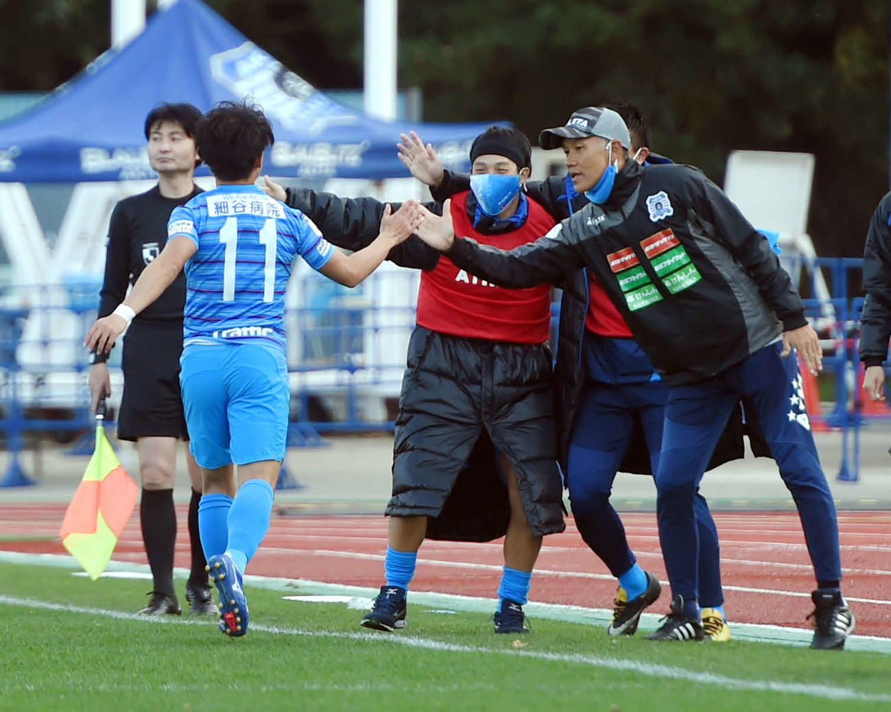 秋田対讃岐　先制点を奪った秋田MF久富とタッチを交わす吉田監督（右）（撮影・相沢孔志）