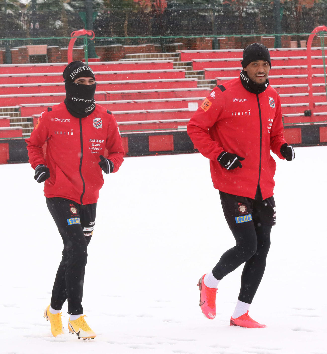 雪が積もったピッチでランニングする札幌FWドウグラス・オリヴェイラ（右）とルーカス