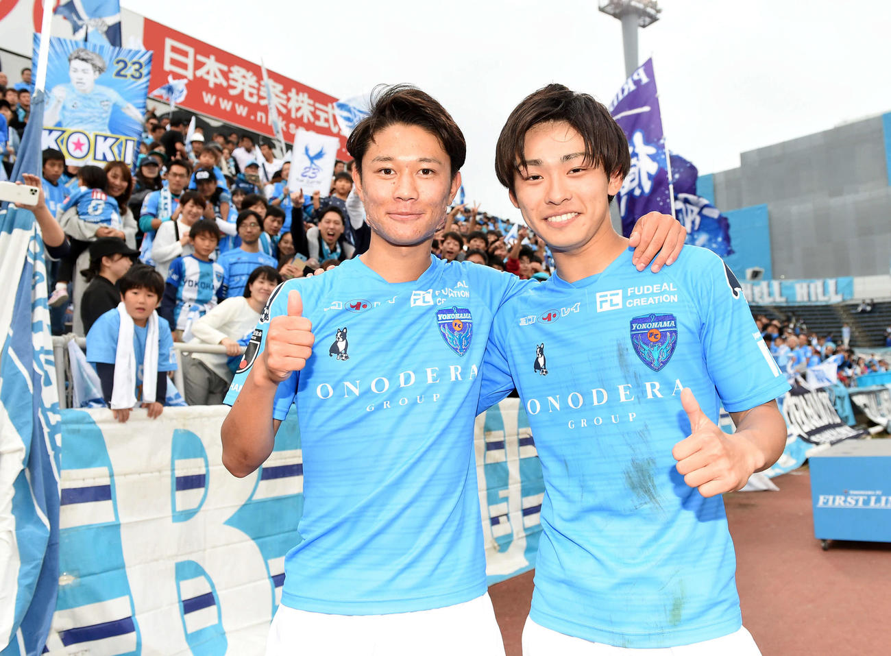 横浜FC対長崎　試合終了後、ファンを背に笑顔を見せる横浜FCのMF斎藤功（左）とFW斉藤光（2019年11月3日撮影）