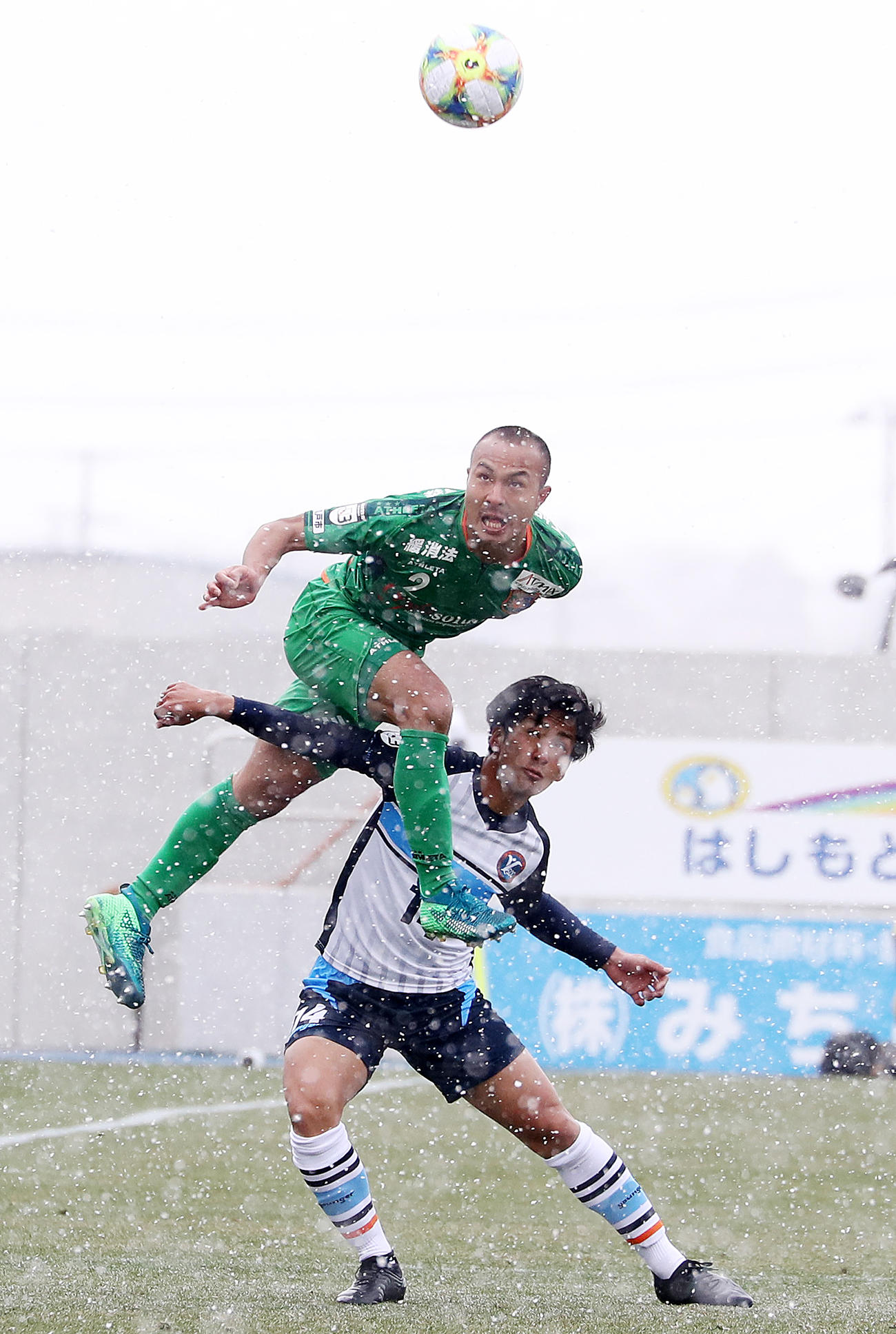 19年3月25日八戸対YS横浜　雪の中、ヘディングで競り合う八戸DF中谷（上）（撮影・野上伸悟）
