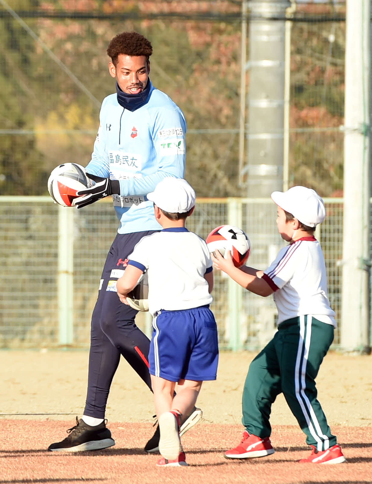 小学生と一緒にボールを運ぶいわきFC・GK白岡（奥）（撮影・相沢孔志）