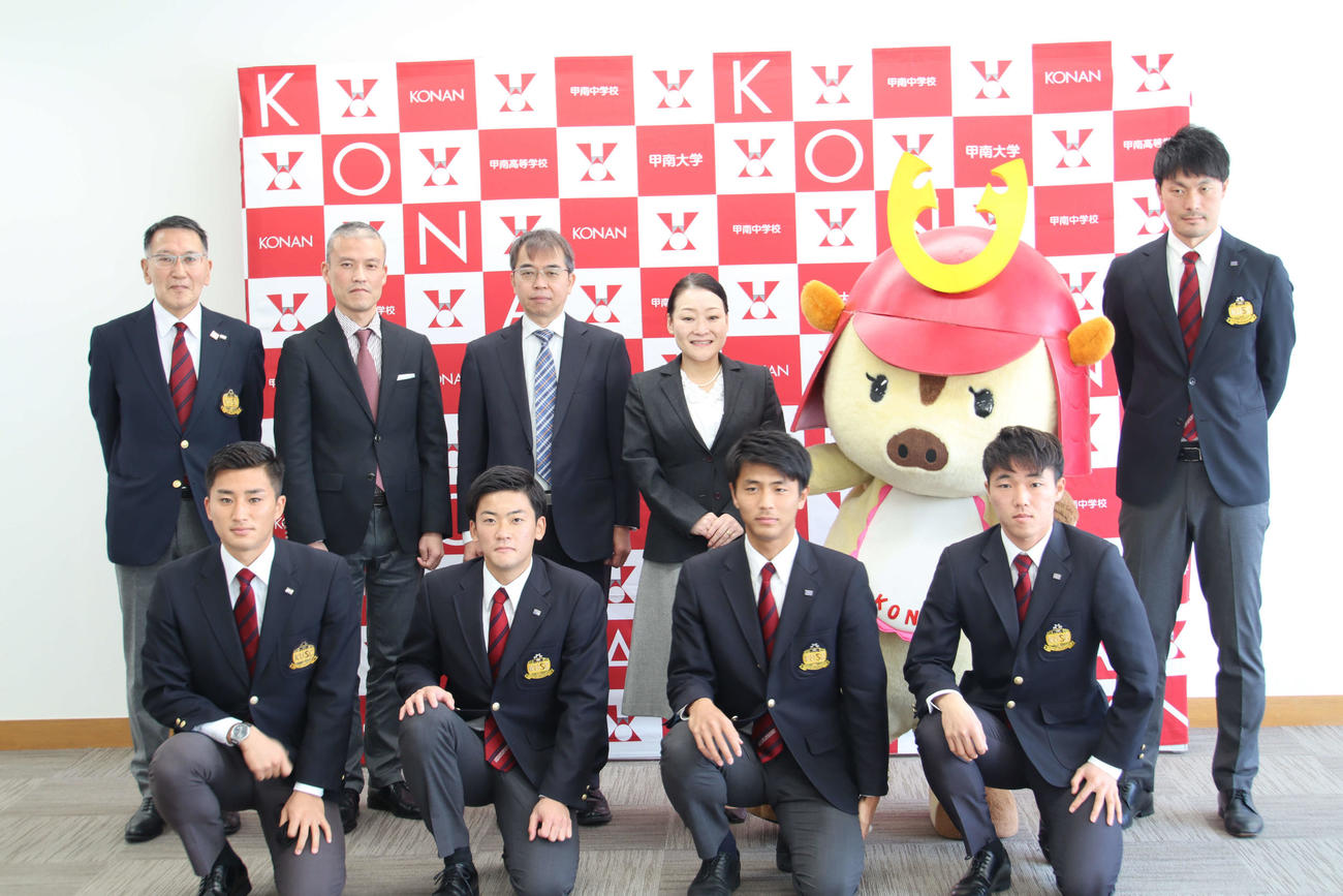 上段左から、西松豊サッカー部強化支援委員長、渡邉順司学生部長、村島貴之副学長・スポーツ強化支援室長、中井伊都子学長、甲南キャラクターなんぼーくん、柳川雅樹監督　下段左から原拓海副将、森大輔主務、木村太哉主将、森章二副将