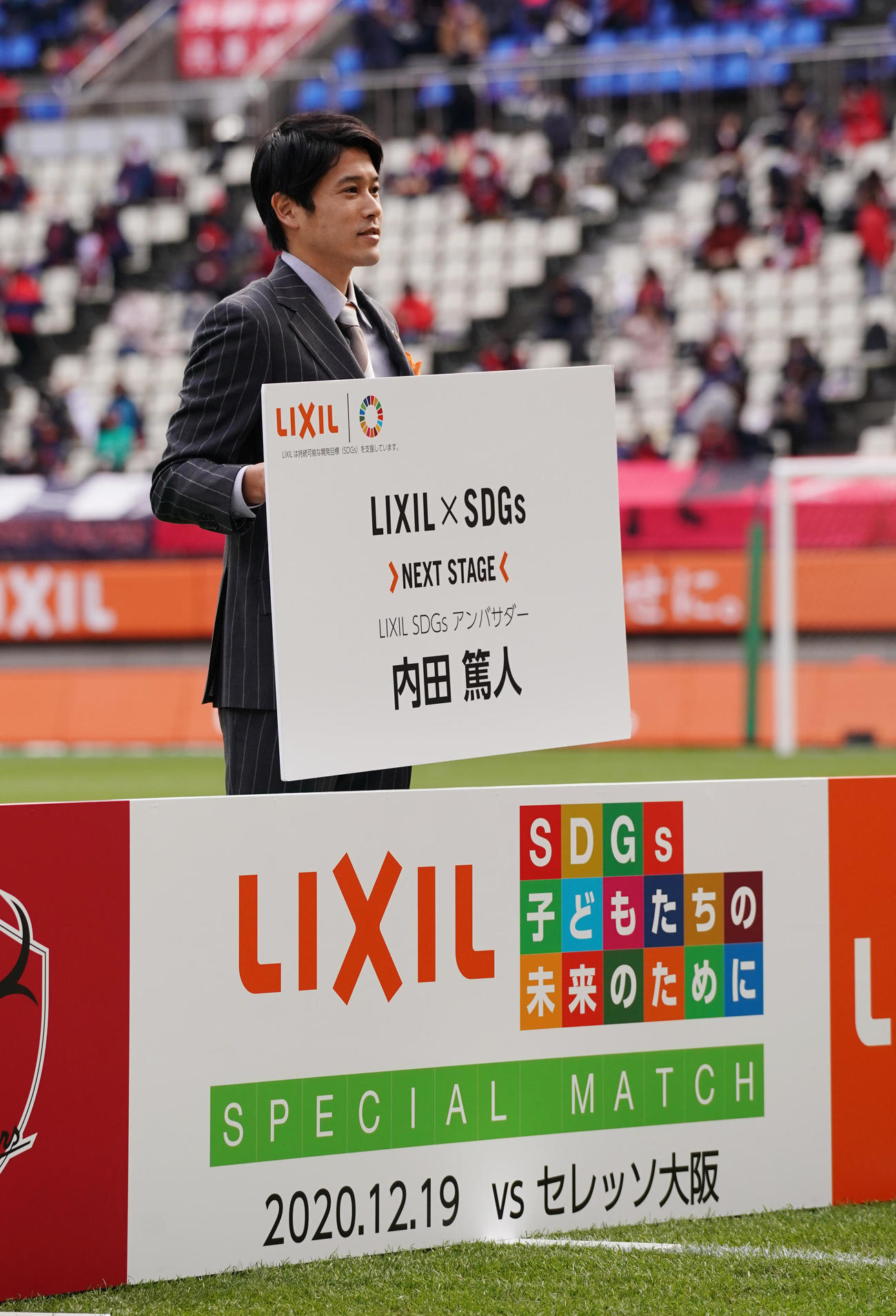 「LIXIL×SDGs　NEXT　STAGE」のプロジェクトアンバサダーに就任し、ボードを手に記念写真に納まる内田氏（撮影・菅敏）