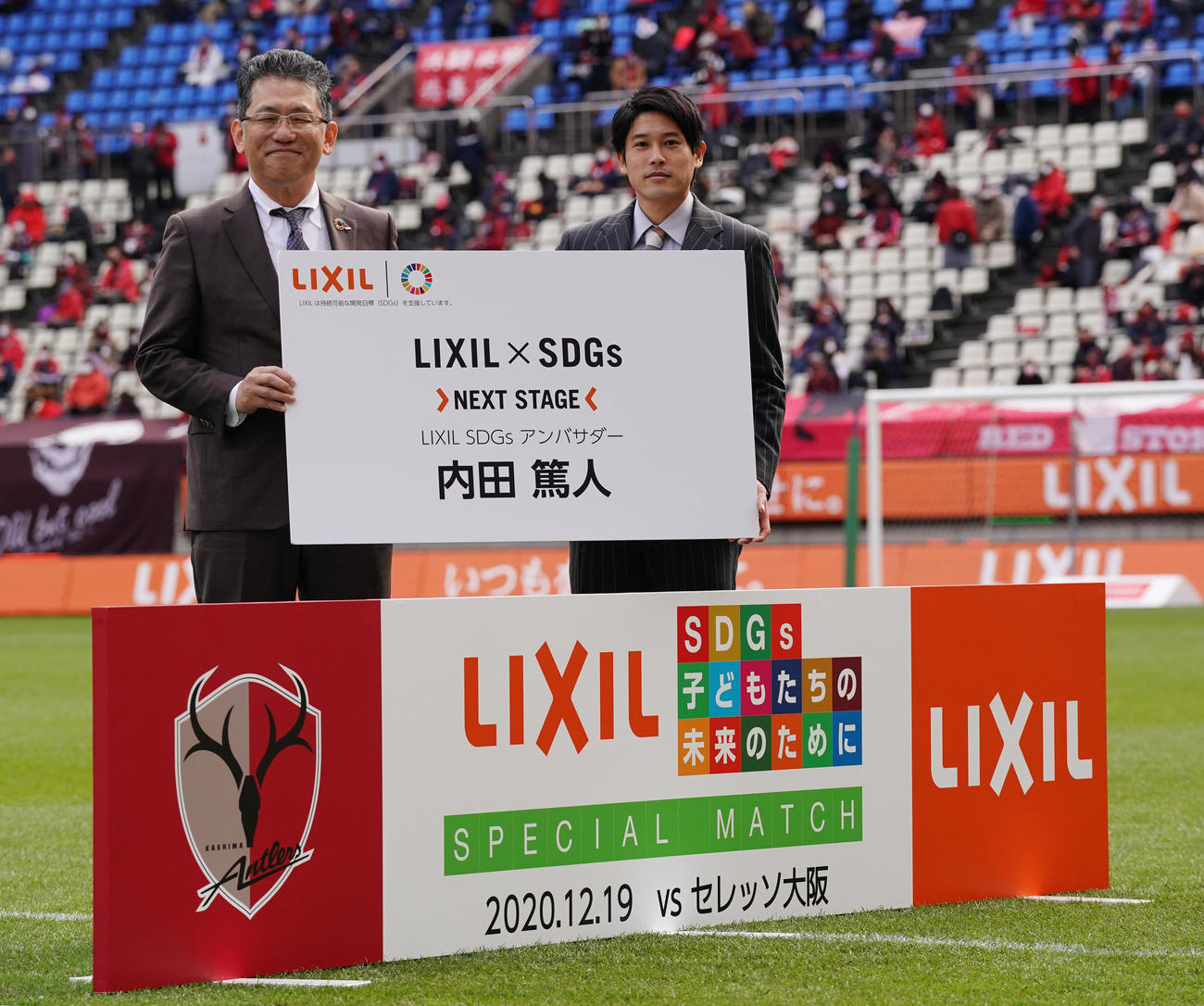 「LIXIL×SDGs　NEXT　STAGE」のプロジェクトアンバサダーに就任し、ボードを手に瀬戸社長（左）と記念写真に納まる内田氏（撮影・菅敏）