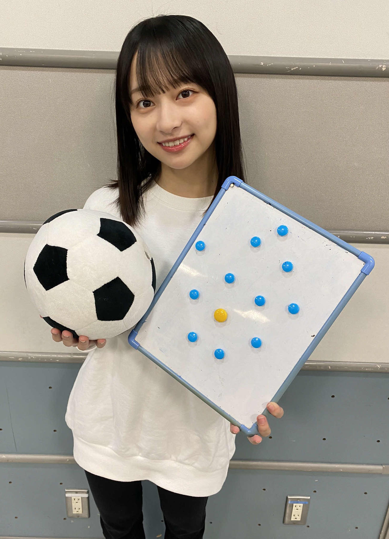 サッカーボールと戦術ボードを持って写真におさまる日向坂46の影山優佳